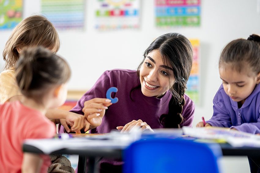 Una maestra trabaja con letras junto a sus alumnas en el aula