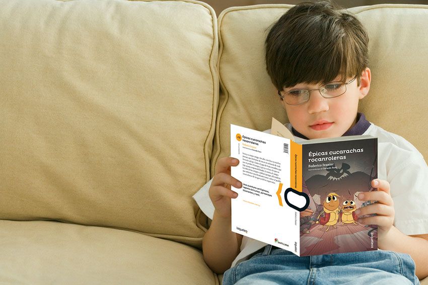 Un niño lee un libro de Loqueleo sentado en un sillón