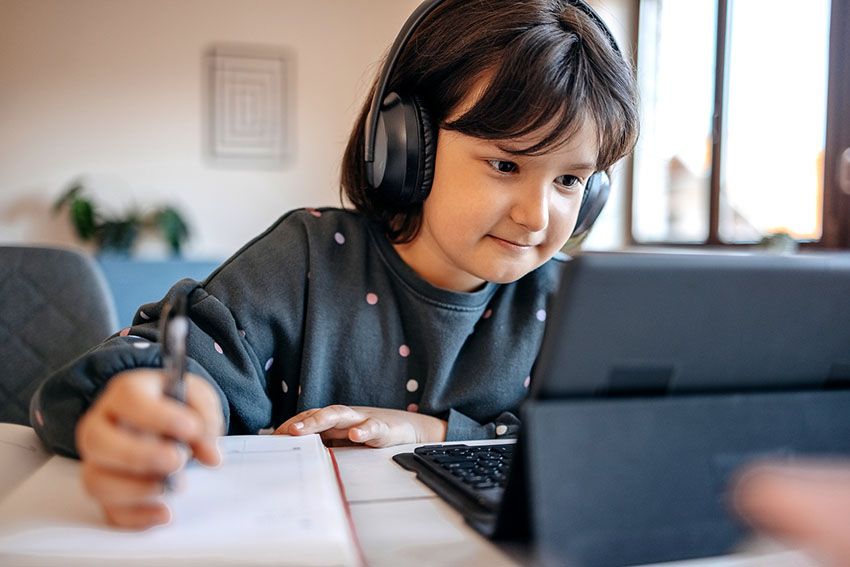 Un niño con auriculares estudia con una tablet y un cuaderno